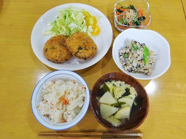 豆腐と野菜のメンチカツ、しらたきとほうれん草の和え物、筍の和風ポテトサラダ、筍とわかめのスープ、桜えびの炊き込みご飯がお皿に盛りつけられてテーブルに並べられている写真