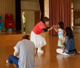 山田先生が中腰になり参加者の女の子と両手でタッチをしている写真
