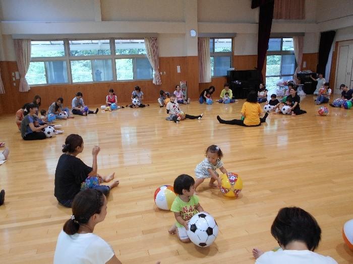 参加者が座って大きな円を作りボールを使ったアクティビティをしている写真