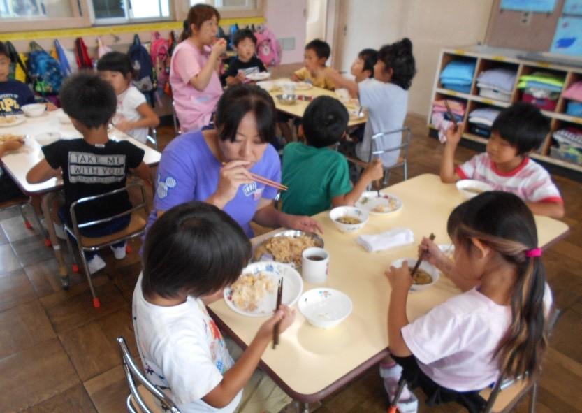 園児たちと一日保育士体験のお母さんが一緒に給食を食べている写真