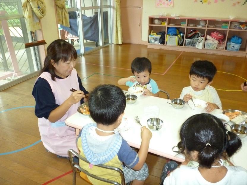 4人の子供たちと一緒に給食を食べている保護者の写真