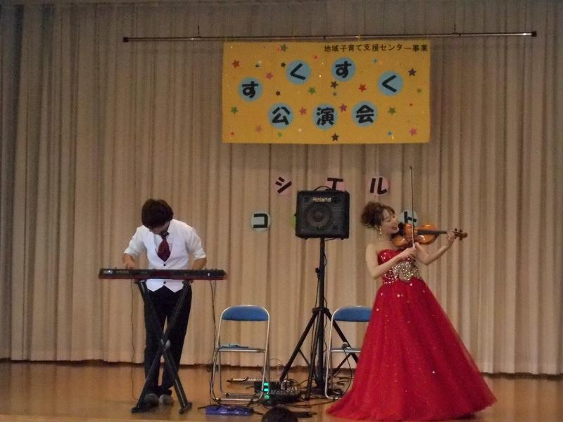 立ってキーボードを演奏する男性とバイオリンを演奏している女性の写真