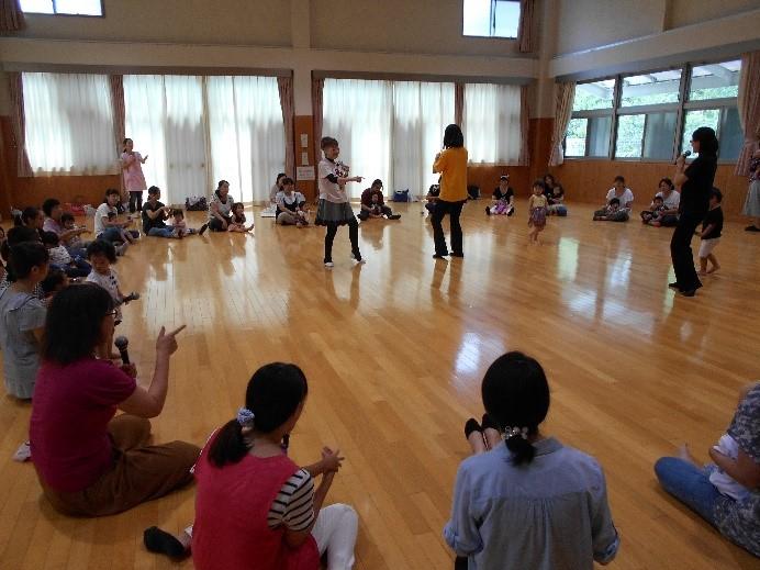 参加者が座って大きな円を作り、円の中央に山田先生が参加者と立っている写真