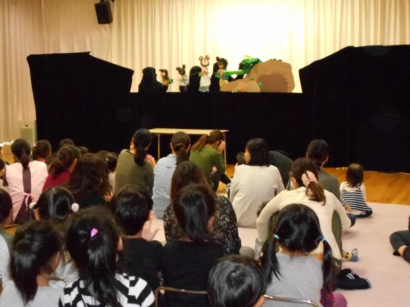 舞台にて人形劇が開催され、それを観劇している参加親子の写真