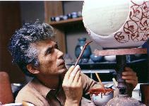 田村 耕一がまるい形の陶器に筆で絵付けをしている写真