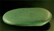 深い緑色の平べったい楕円形の形をした固い石のような作品の写真