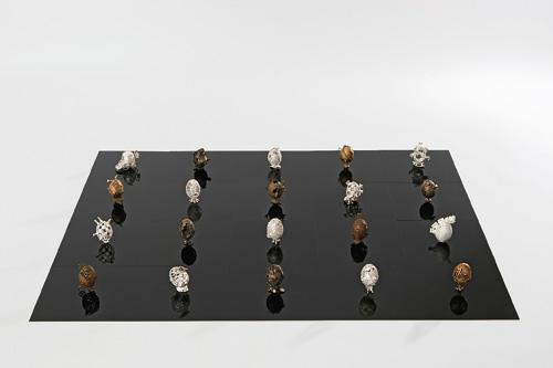 四角い黒い板の上に20個の卵が様々なモチーフで制作されたユニークな作品の写真