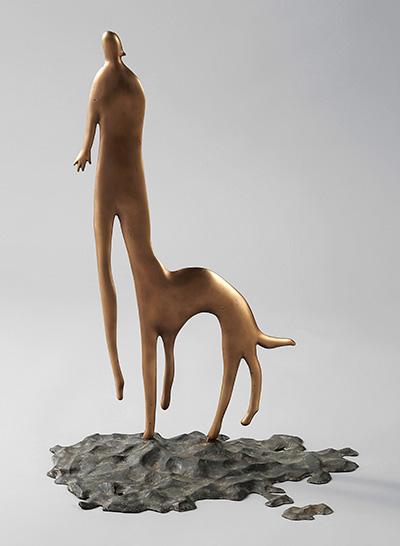 砂浜を表現した鋳金の上に立つ犬の体と犬の首から上が人の片方の脚とくっついている人の作品