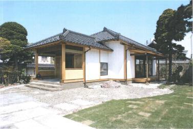 寄棟屋根が2つある和風の家で、家の周りに砂利と芝生が広がっている写真
