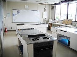 ガスコンロや水道などの調理台や調理道具がある実習室の写真