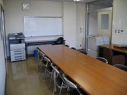 長机の周りに椅子が並んでいて、部屋の隅にはコピー機が置いてある活動室の写真