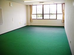 緑の床で何もおかれていない児童室の写真