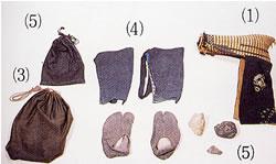 大小黒い巾着袋が各ひとつずつ、紺脚絆と足袋覆が各1足、小石が3つ、しば草を糸で編んだ山岳帽の写真