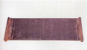 一枚の木の板の両端に取っ手をつけてあり、その板の表面には文字が彫られている中根東里学則版木の写真