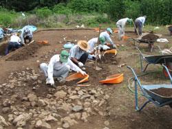 唐沢山麓の根小屋地区で桑を使って土を掘り遺跡の発掘調査をしている調査員の方たちの写真