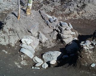 免鳥城跡の本丸跡の確認調査時に発見された井戸跡と思われる石が土の中から出てきた写真