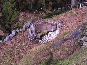山の斜面にできた窪地に石が積み上げられた七輪窯の跡の写真