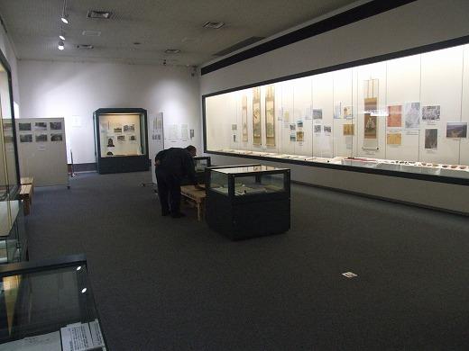 郷土博物館との連携による記念企画展にて館内に展示してある唐沢山城跡に関する資料と展示品を見ている男性の写真