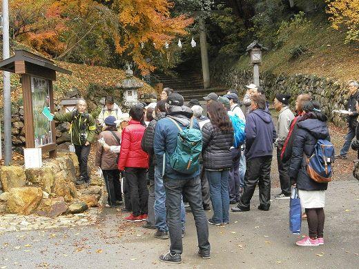 史跡ガイドの方が案内板を指して説明し多くの人が聞いている写真