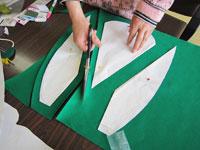 緑の画用紙に模型の形を型どりハサミで切っている写真