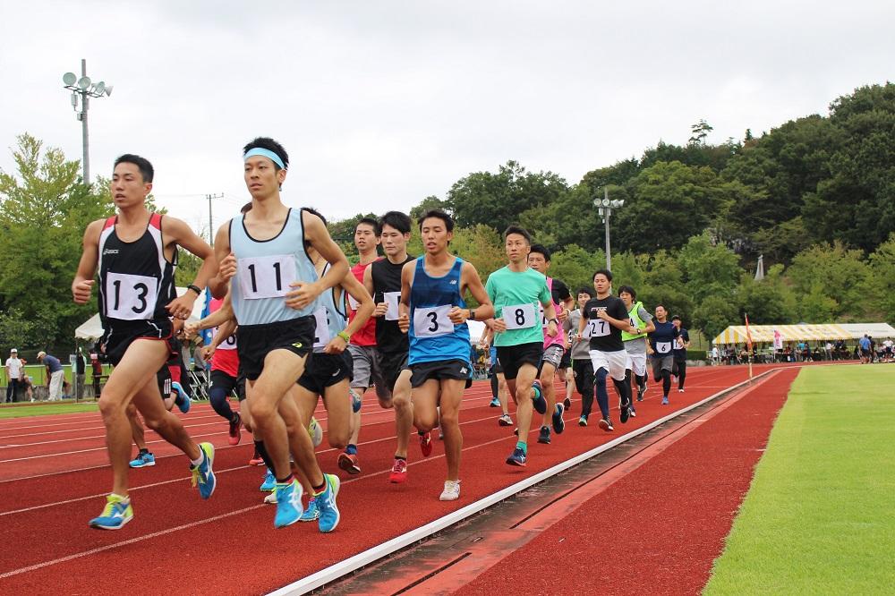 競技場を走り競っている男性選手たちの写真