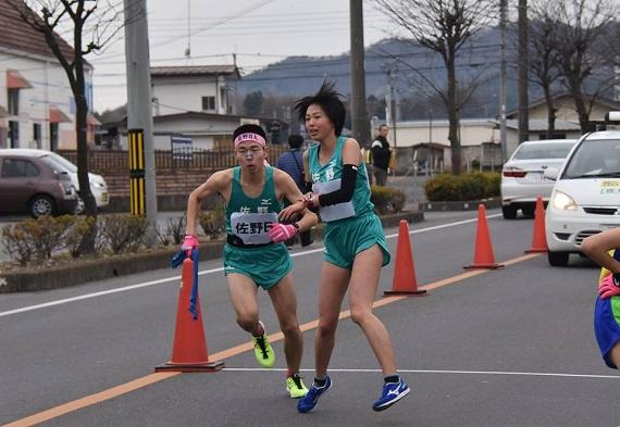 女性選手が男性選手に襷を渡し勢いよく駆け出している男性選手の写真