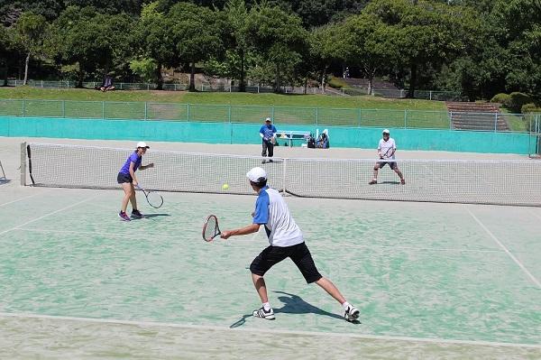 テニスの男女混合ペアの試合で選手がボールを打とうとラケットを構えている写真