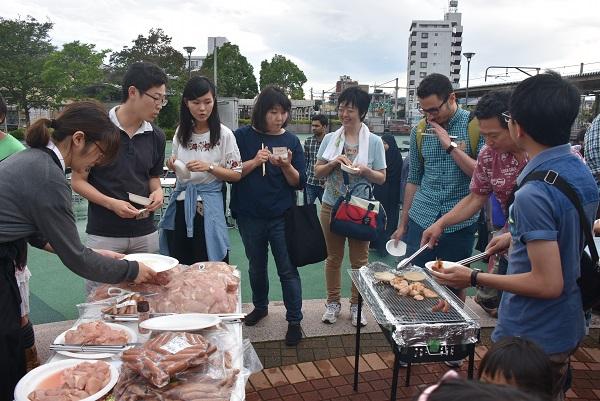 バーベキューコンロの周りに集まる人達の写真