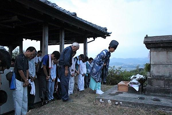 神主を先頭に祠の前で礼をする人達の写真