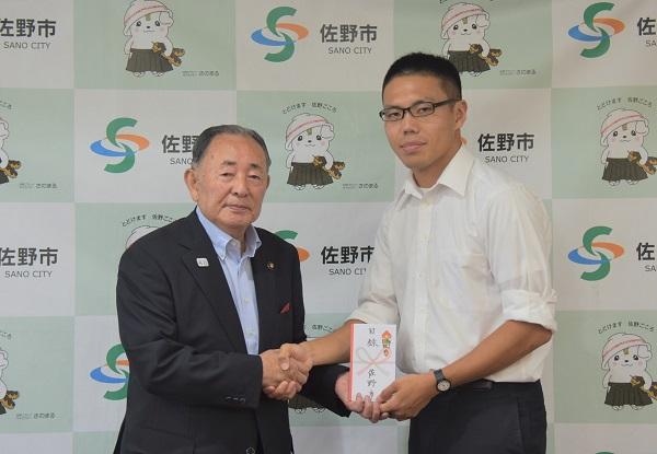 市長と両手で握手をしている池田友仁さんの写真
