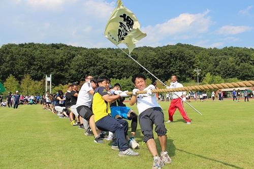 綱引きの競技で力を合わせて綱を引っ張っている写真