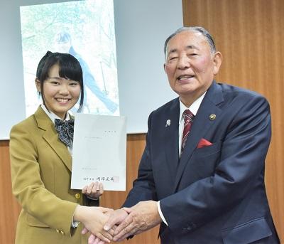 制服を着た堀優衣さんと握手をしている佐野市長の写真