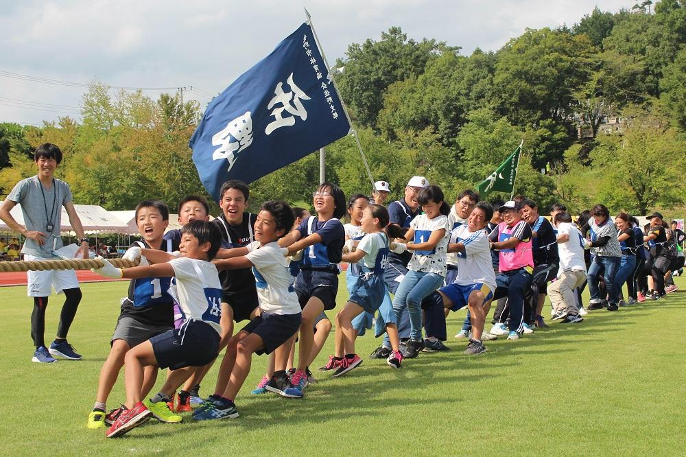 綱引きをしている選手と佐野と書かれた旗を振りながら応援している方の写真