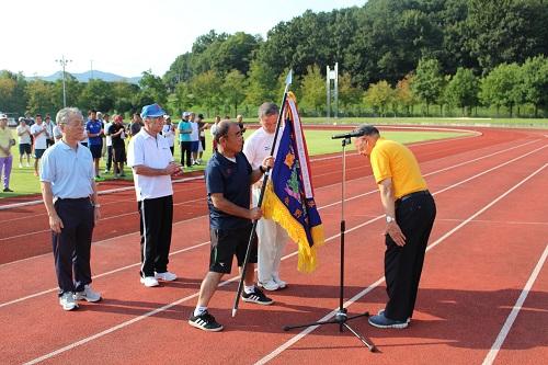 閉会式で男性の代表者が優勝旗を受け取った写真