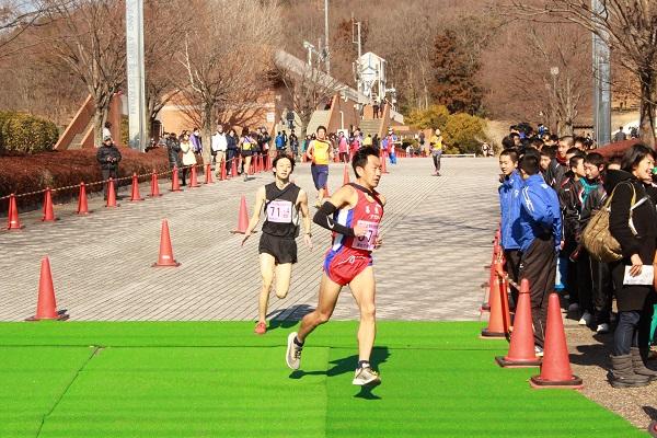 カーブのコースで沿道で応援される中選手が走っている写真